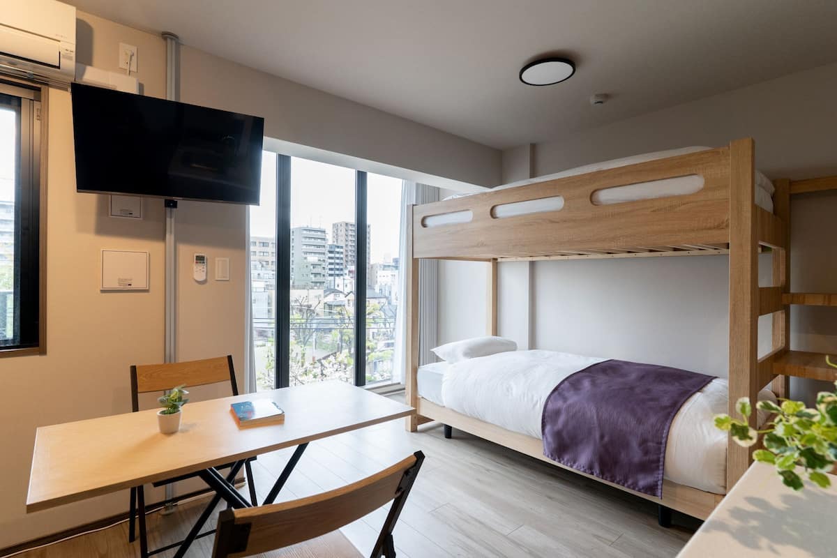 A bunk bed room with a TV, a table, and a chair.