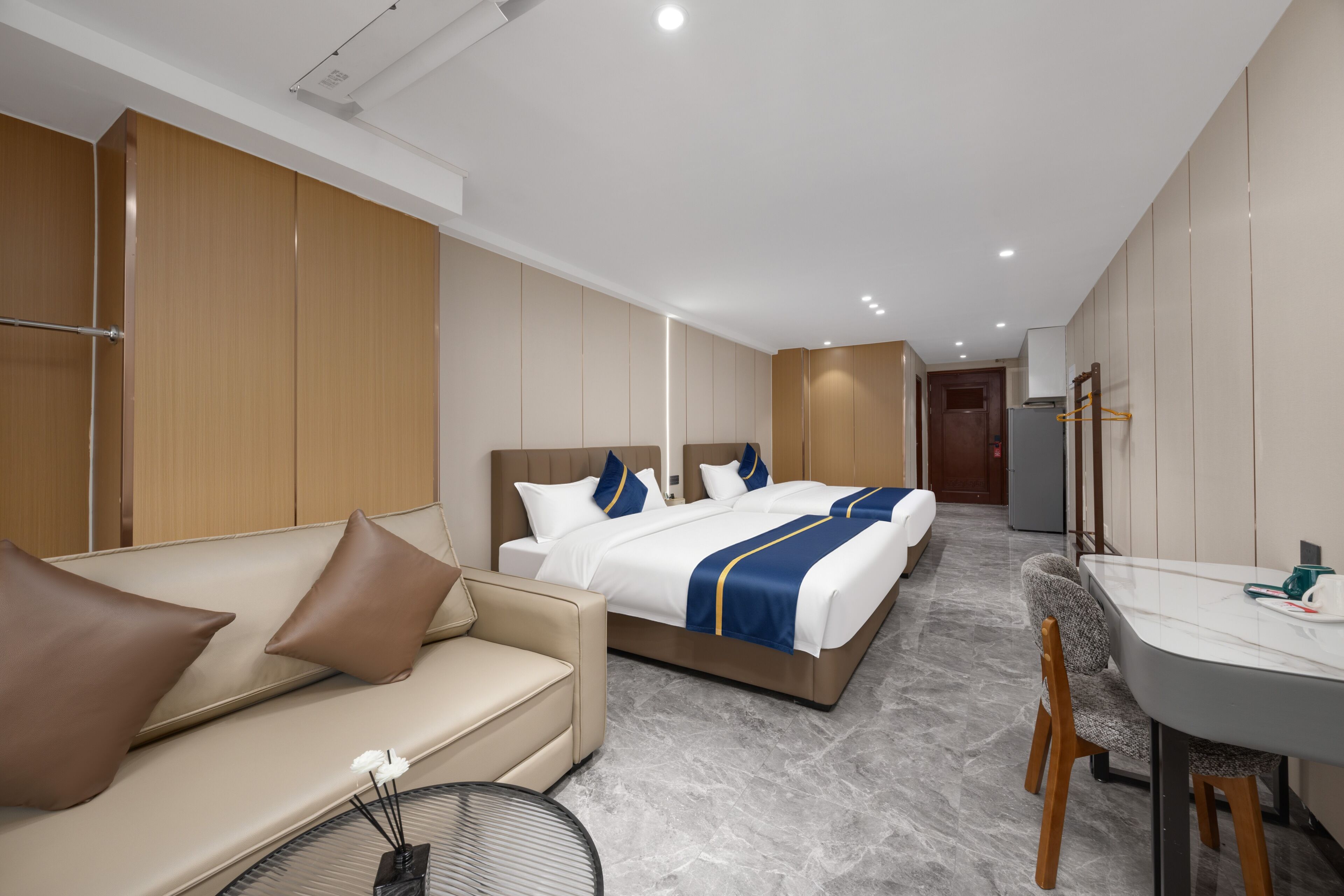 A hotel room with a bed, a sofa, a desk, and a chair.
