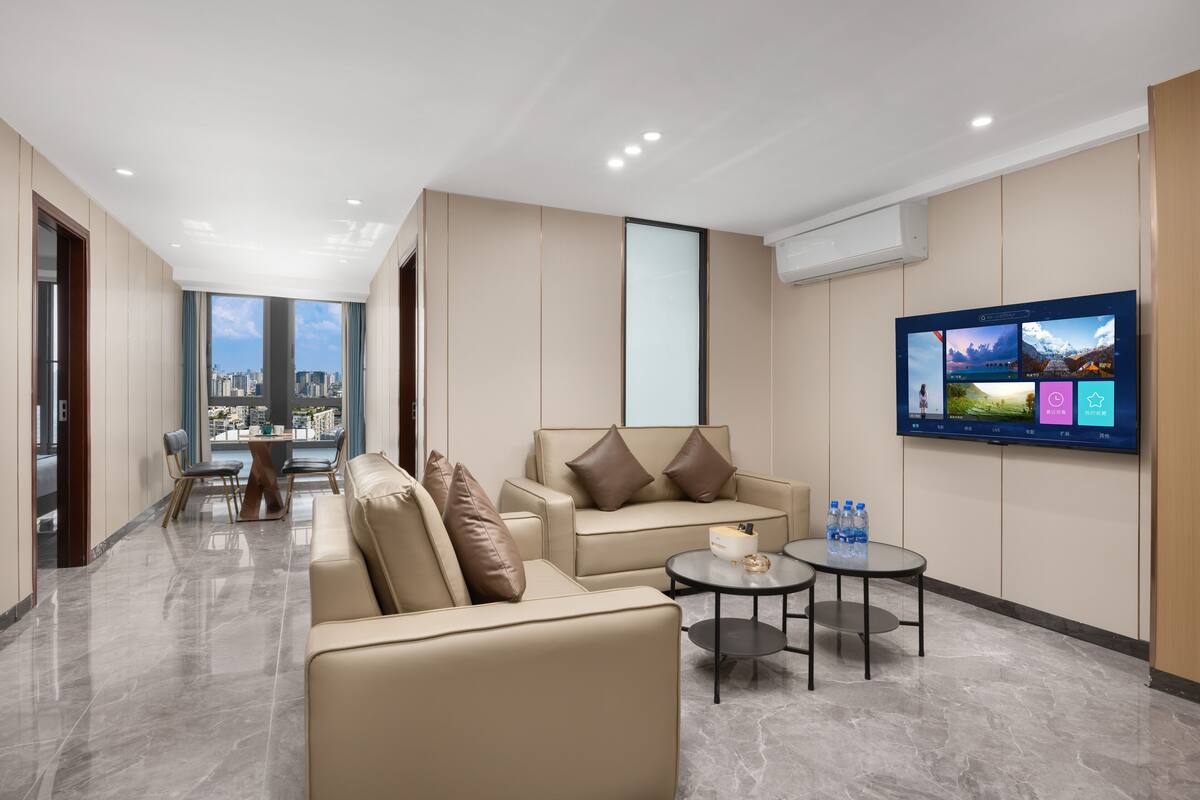 A modern hotel lobby with a seating area, a flat-screen TV, and a city view.