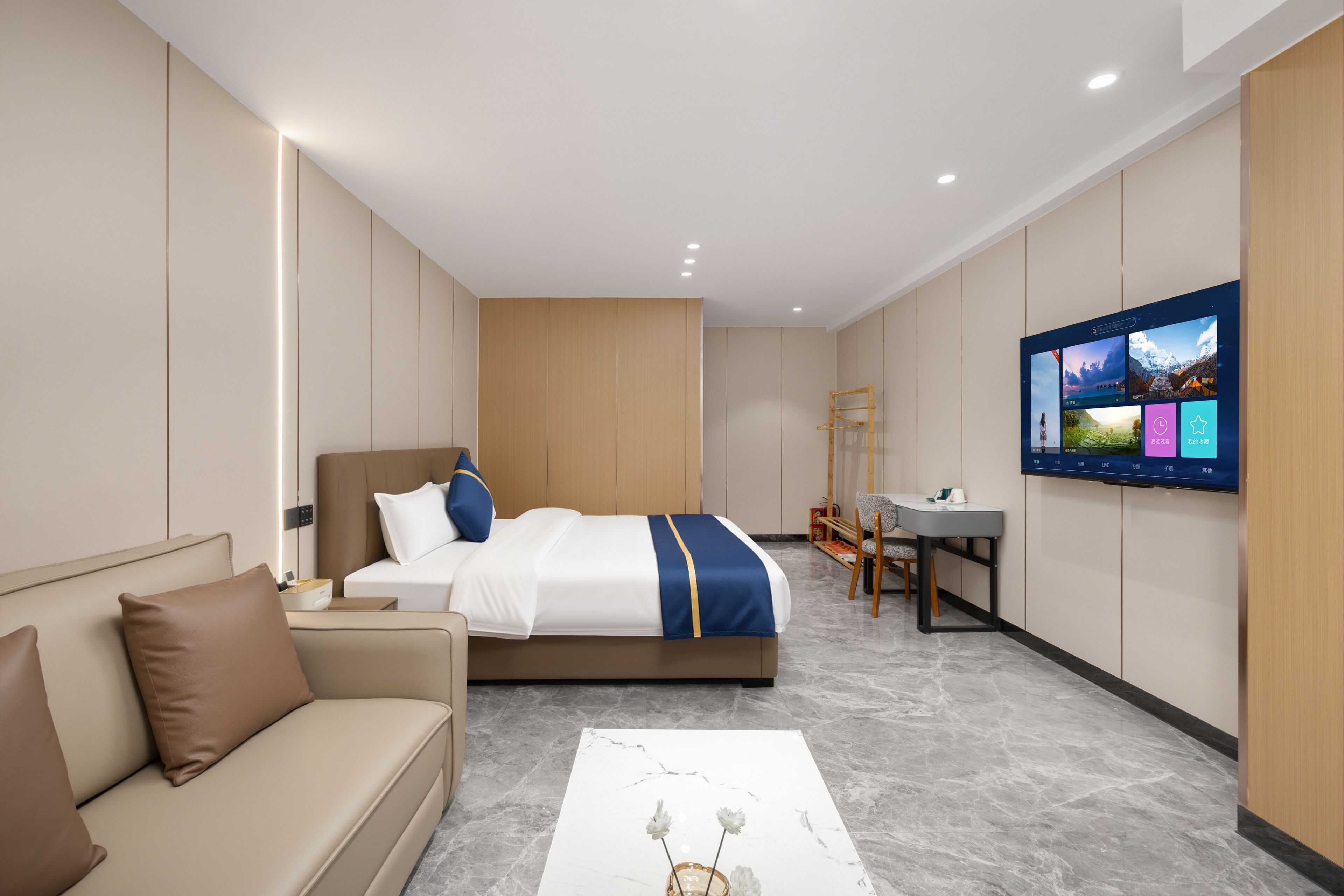 Una habitación de hotel moderna con cama, sofá, escritorio y televisor en la pared.
