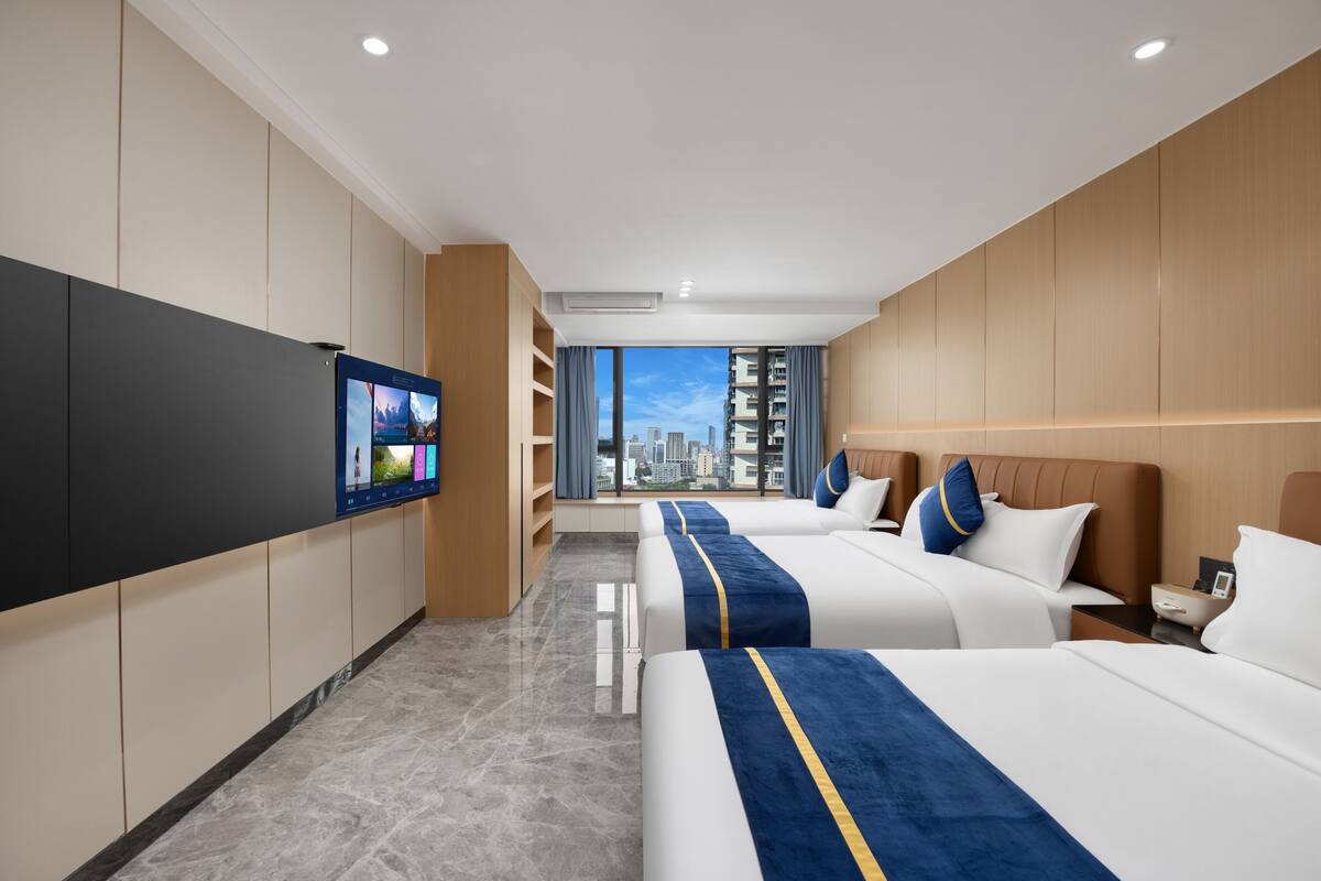 A hotel room with two beds, a TV, a city view, and a modern design.