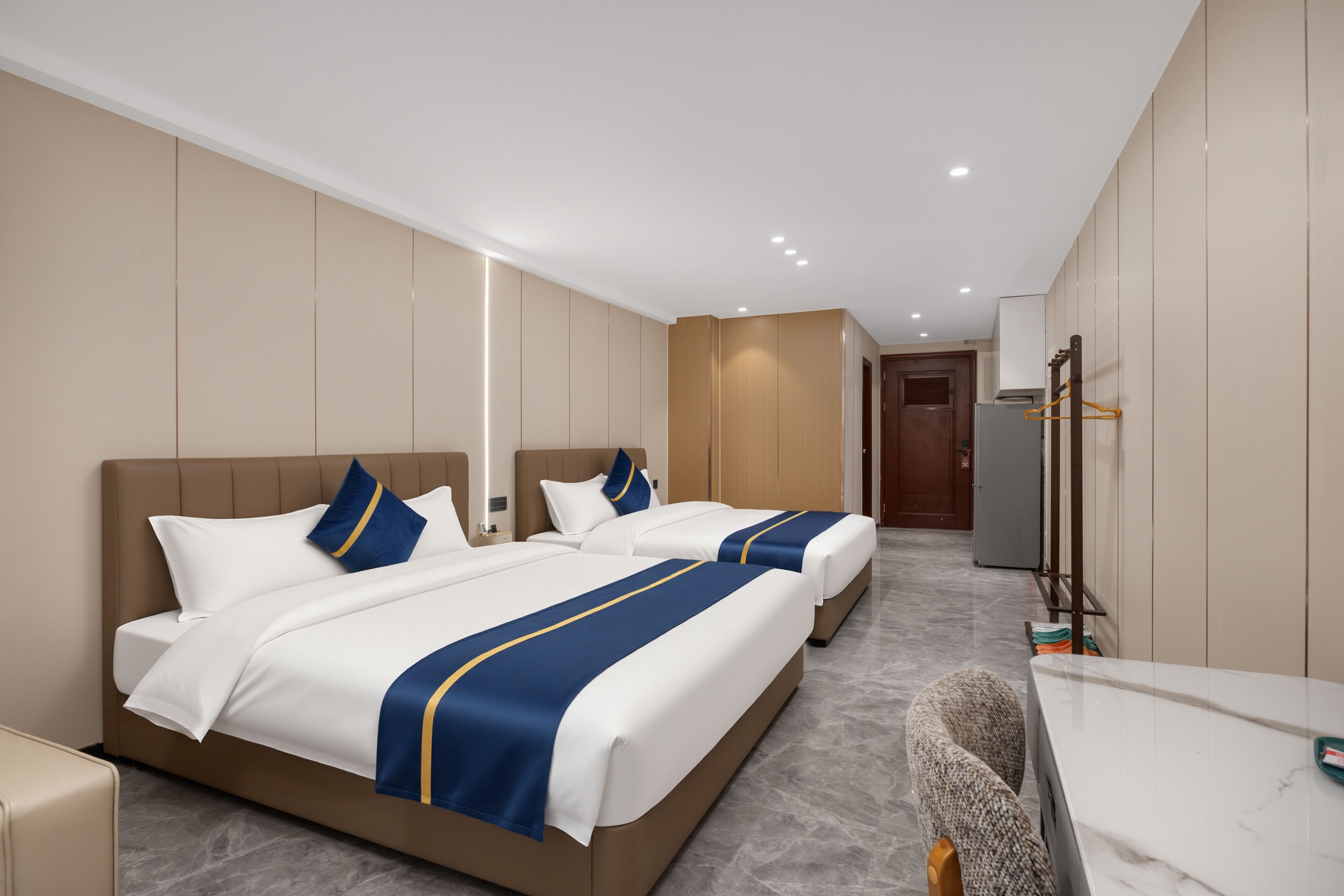 Una habitación de hotel con dos camas, un escritorio y un espejo.