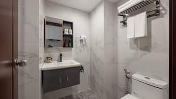 Un baño con lavamanos blanco, mueble oscuro y un inodoro.