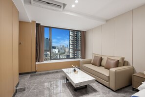 A modern living room with a sofa, a coffee table, and a view of a cityscape through large windows. - Weekend International Apartment- Beijing Rd Mingyue Mansion (Guangzhou)