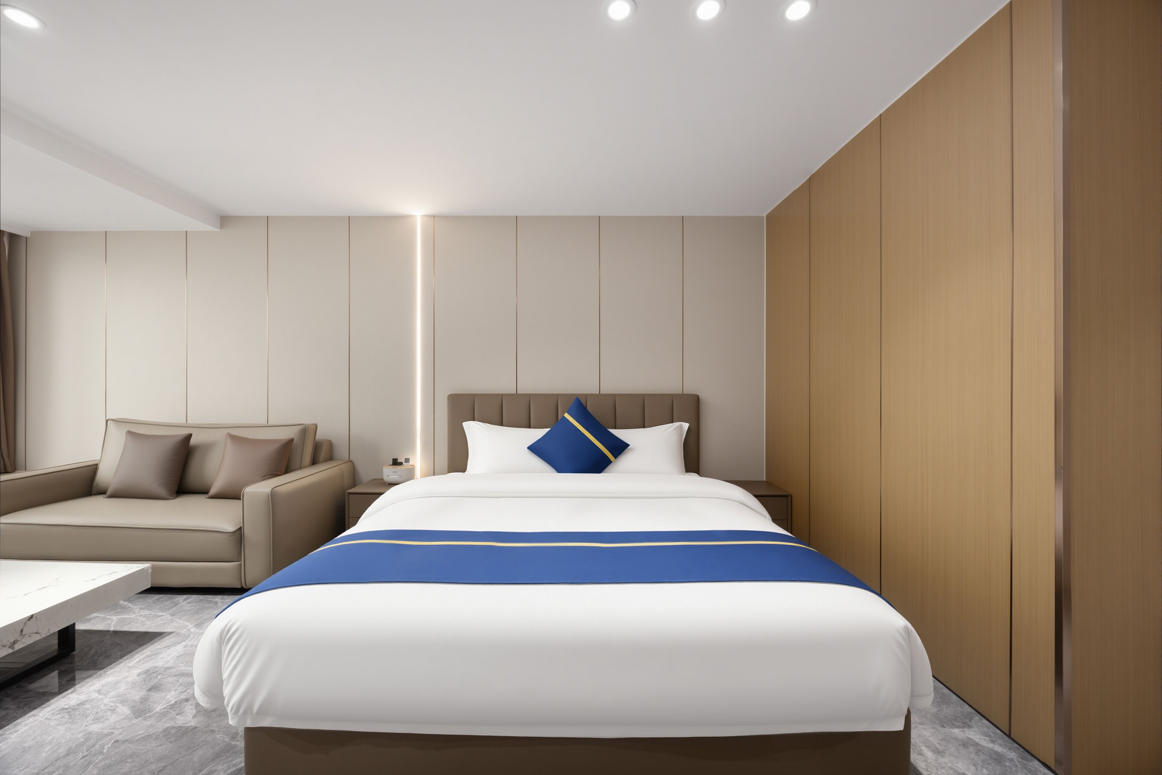 Una habitación de hotel moderna con una cama, un sofá y una mesita de noche.