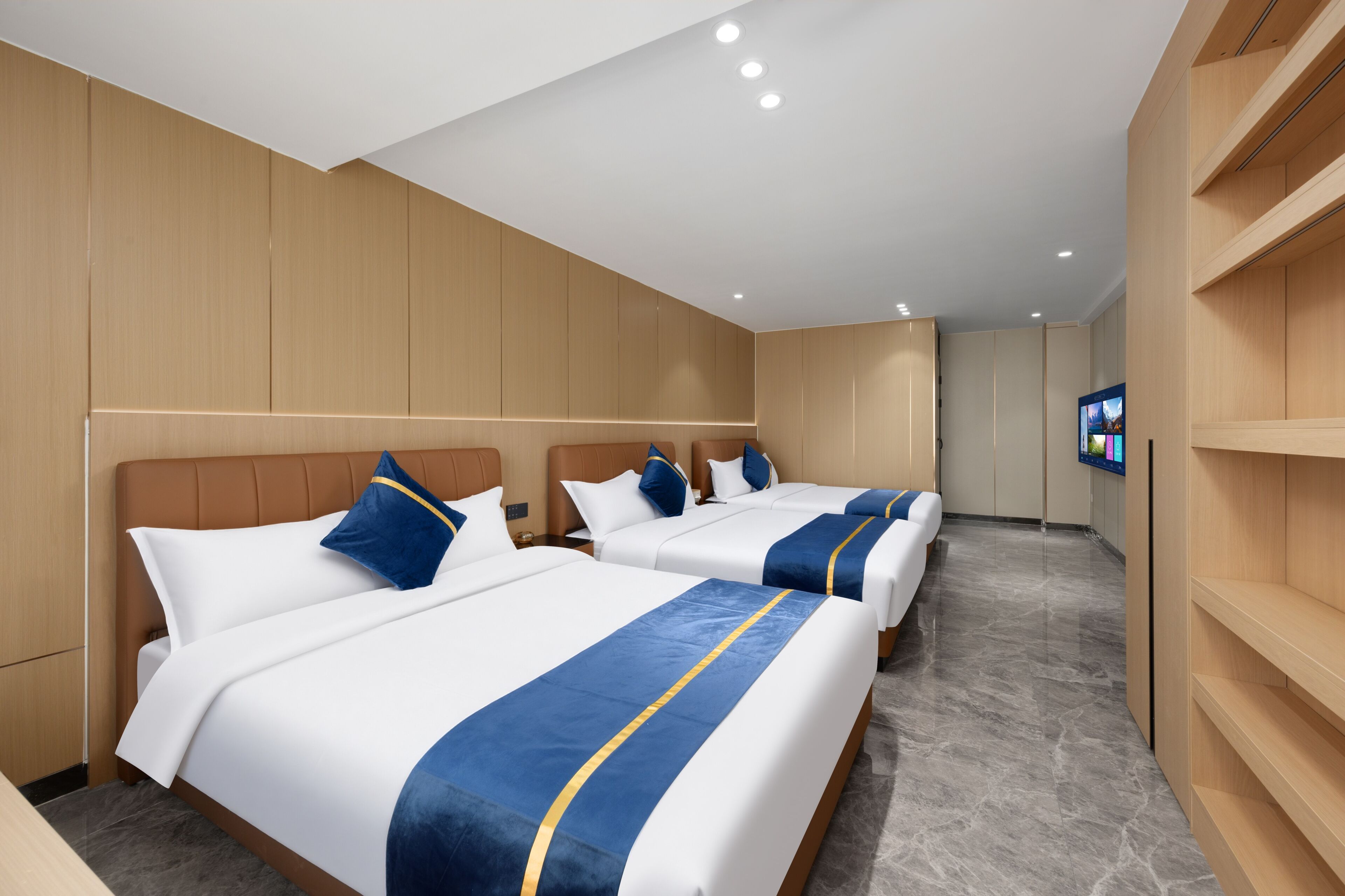A hotel room with three beds, wooden paneling, a flat-screen TV, and a marble floor.