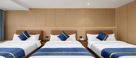 A hotel room with three beds, wooden panel walls, and a nightstand with a lamp.