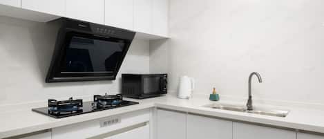 A modern kitchen with a built-in microwave, a coffee maker, a gas stove, and a sink.