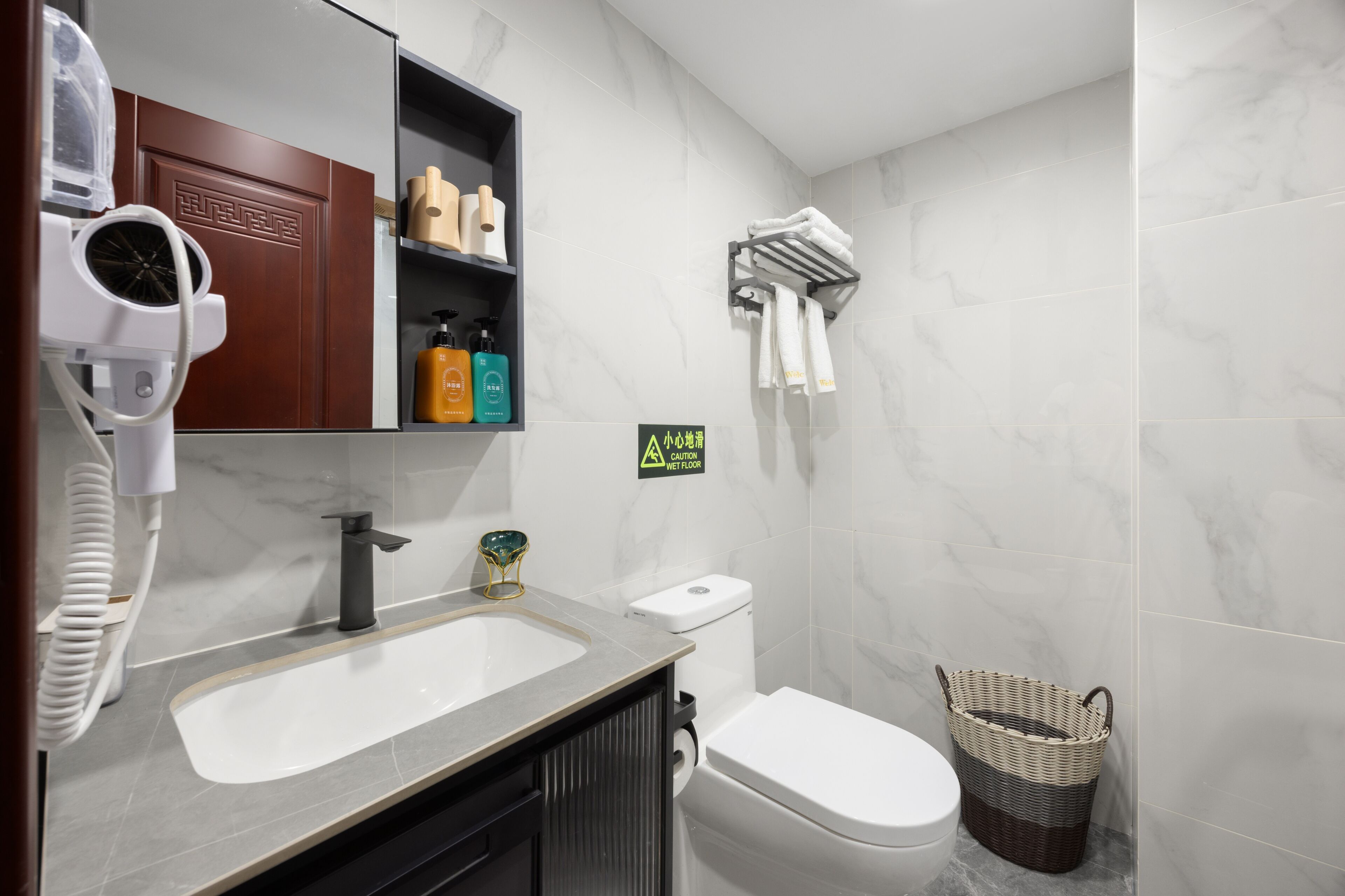 A bathroom with a sink, toilet, and a hairdryer on the counter.