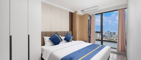 A hotel room with a bed, wardrobe, and a city view.