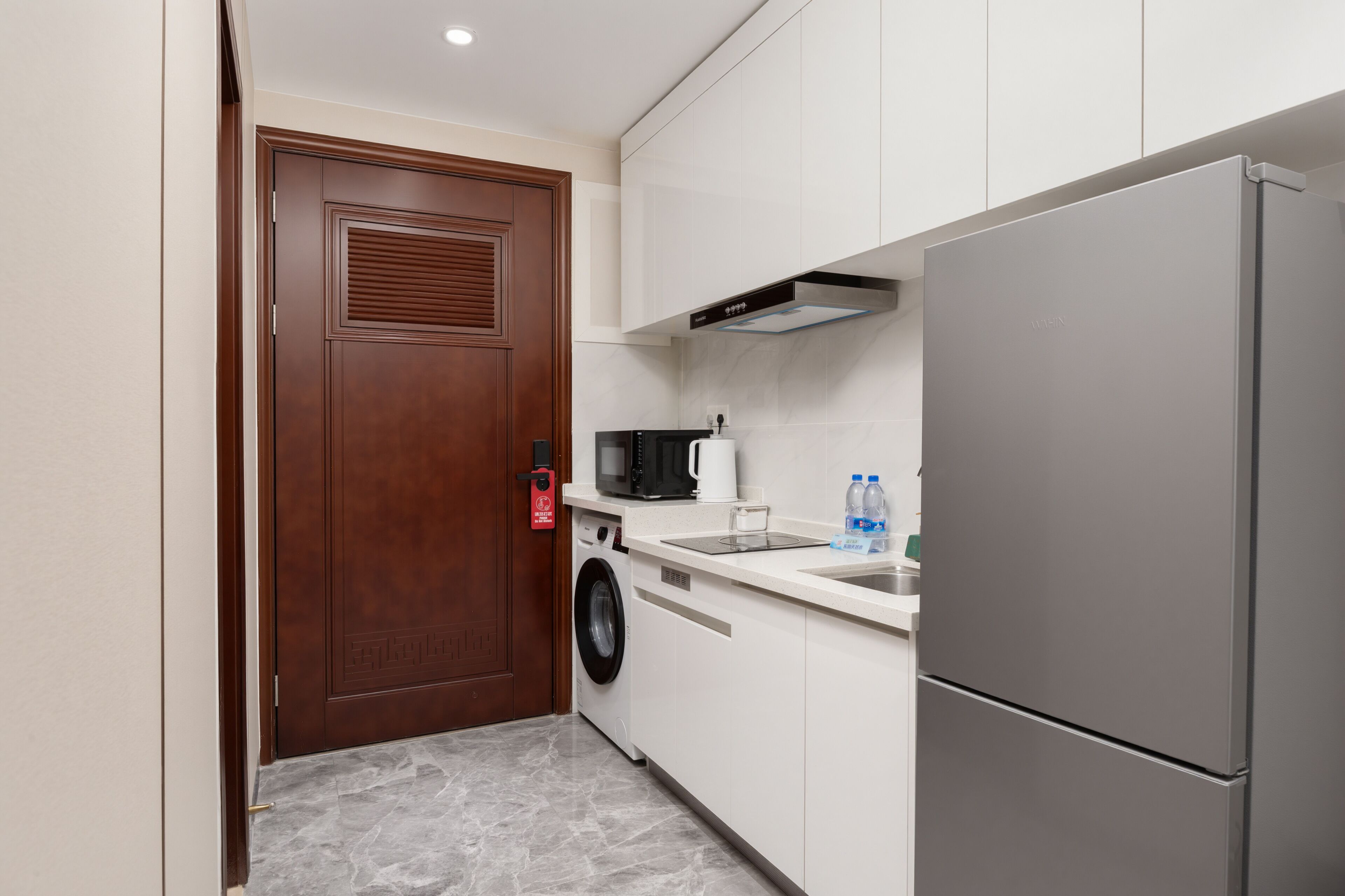 A compact kitchen with a washing machine, a microwave, and a refrigerator.