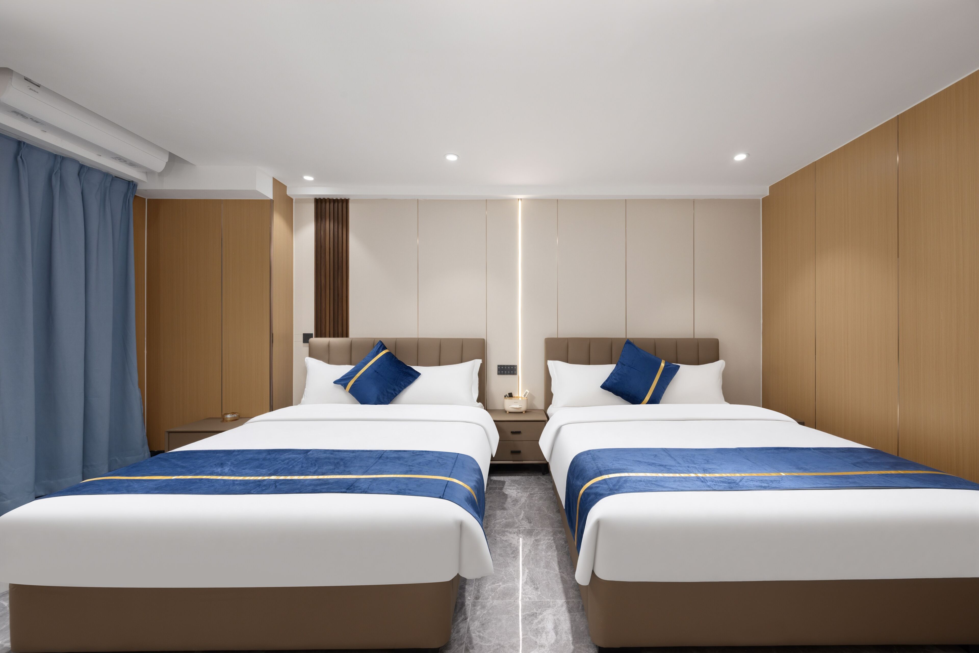 Une chambre d’hôtel avec deux lits, une table de chevet, un miroir et une fenêtre avec des rideaux.