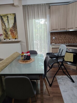 A modern kitchen with a dining table, chairs, a refrigerator, and a microwave.