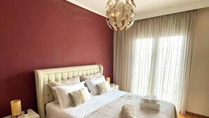 A neatly made bed with a white headboard, a decorative ceiling light, and a patterned rug.