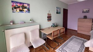 A dining area with a table and chairs, a radiator, a hanging light fixture, and a dresser.