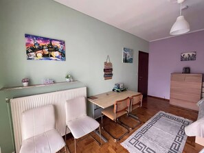 Ein Essbereich mit Tisch, Stühlen, einem Heizkörper, einer Pendelleuchte und einer Kommode.
