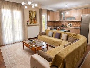 A living room with a sofa, coffee table, and a kitchen in the background.