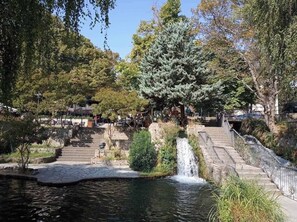 A park with a waterfall, stone steps, and a pond.