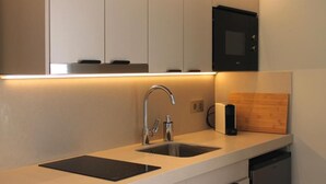 A modern kitchen with a double sink, stainless steel faucet, and a microwave above the counter. - Makai Bungalows (San Bartolomé de Tirajana)