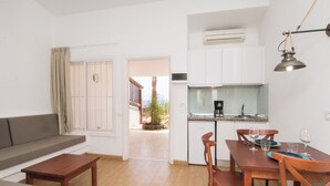 A compact living space with a kitchenette, dining area, and a view through an open door. - Makai Bungalows (San Bartolomé de Tirajana)