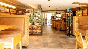 A cozy cafe with wooden furniture, a bar area, and shelves stocked with various items. - Rauris Penthouse with Fireplace (Rauris)