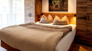 A bed with a wooden headboard, a beige blanket, and pillows. - Rauris Penthouse with Fireplace (Rauris)