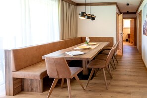 Un comedor con mesa de madera, asientos de banca acolchados y una lámpara colgante.