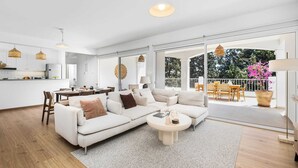 En moderne stue med sofa, sofabord og spiseplads.
