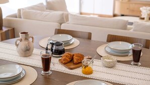 Morgenmad med croissanter, kaffe og et kande juice på et bord.