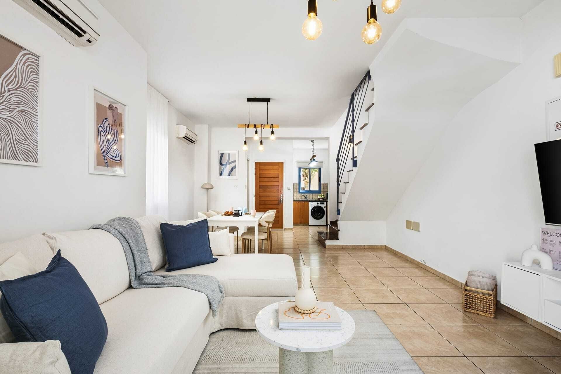 A modern living room with a sofa, a coffee table, and a staircase leading to a dining area.