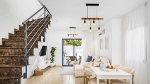 Een modern interieur met een trap, een eethoek en uitzicht door een glazen deur.