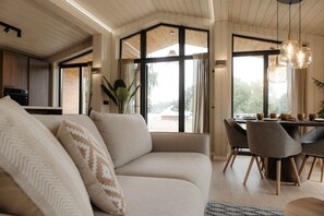 Un salon moderne avec un canapé, une table à manger, des chaises et de grandes fenêtres.