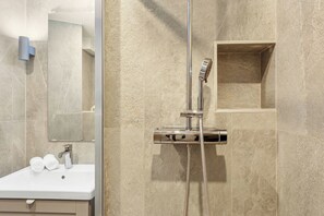A modern bathroom with a shower, a sink, and a mirror. - Bright Parisian 1BR by Champs (Paris)