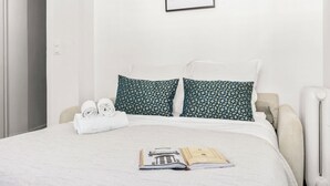 A neatly made bed with two pillows, a rolled towel, and an open book on the bed. - Bright Parisian 1BR by Champs (Paris)