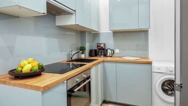 A compact kitchen with a sink, coffee maker, and a washing machine. - Bright Parisian 1BR by Champs (Paris)