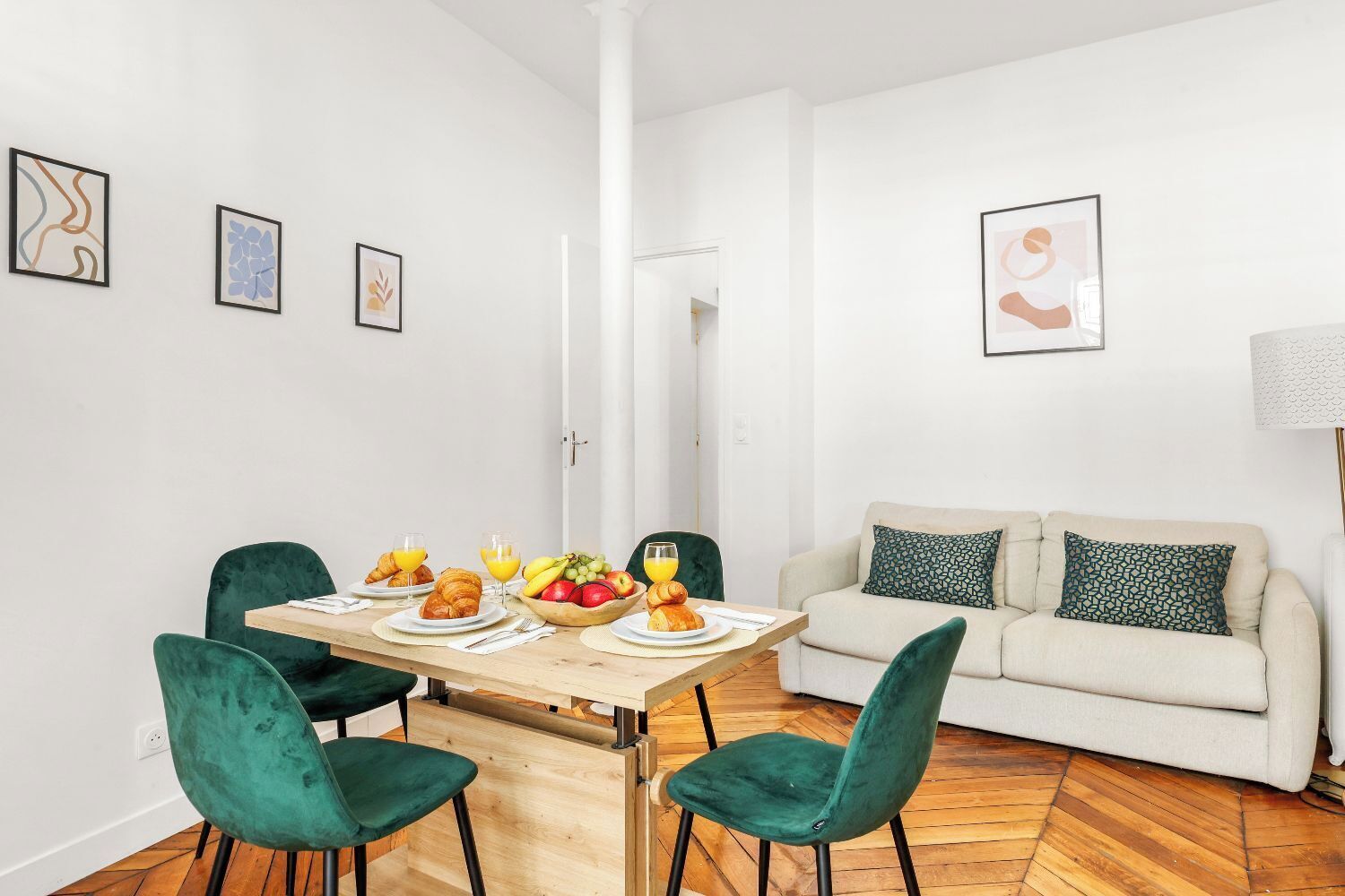 A dining area with a table set for breakfast, a sofa, and a lamp.