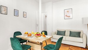 A dining area with a table set for breakfast, a sofa, and a lamp. - Bright Parisian 1BR by Champs (Paris)
