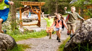 En gruppe mennesker går på en grussti med et træskilt, der står 'OLDWASCHPLATZ'.