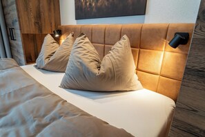 A bed with a headboard, two pillows, and a bedside lamp.
