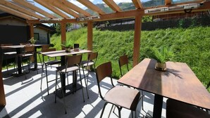 An outdoor patio with wooden tables and chairs, surrounded by a wooden pergola and a view of a lush green landscape. - Rauris Suite with Breakfast & Sauna (Rauris)