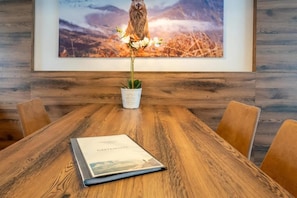 Ein Holzespeisetisch mit einem Buch mit dem Titel 'GASTEMPIER' und einem Blumentopf mit weißen Blüten.