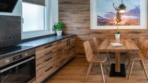 A modern kitchen with wooden cabinetry, a built-in oven, and a dining area with a wooden table and chairs. - Rauris Suite with Breakfast & Sauna (Rauris)
