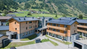 A modern hotel with a central courtyard, multiple floors, and a mountainous backdrop. - Rauris Suite with Breakfast & Sauna (Rauris)