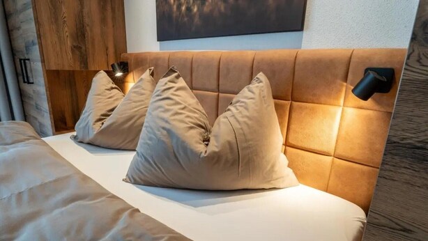 A bed with a headboard, two pillows, and a bedside lamp. - Rauris Suite with Breakfast & Sauna (Rauris)