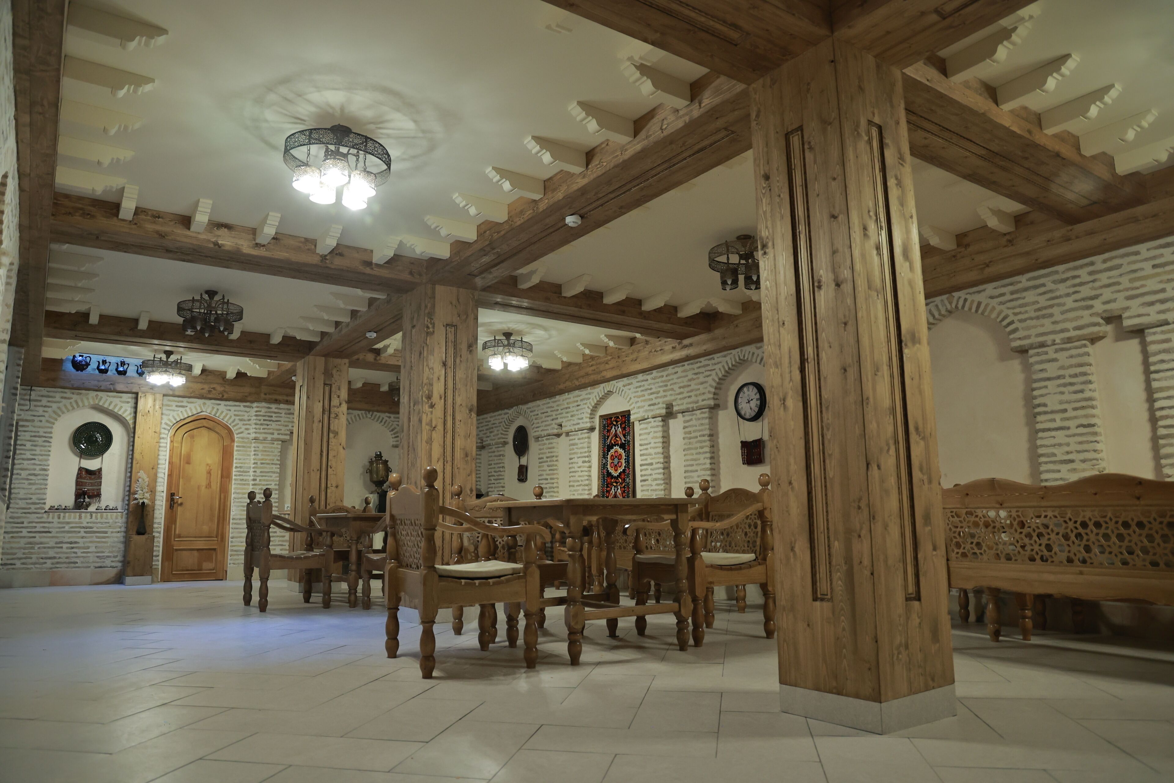 Un'ampia sala con travi in legno, un grande tavolo di legno e diverse sedie.