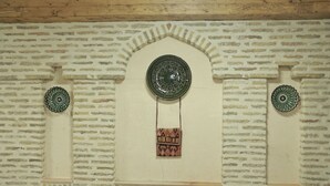 A wall with a brick pattern, a decorative plate, and a hanging bag. - BAKOVUL HERITAGE  (Bukhara)