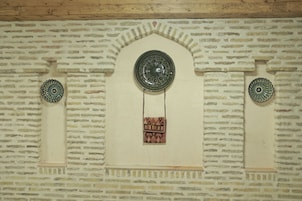 Una pared con diseño de ladrillos, un plato decorativo y un bolso colgante.