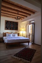 Un dormitorio con cama de madera, alfombra estampada, candelabro y tapiz en la pared.
