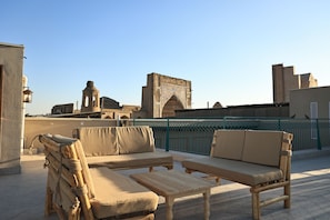 Terraço no telhado com mobiliário externo, vista da arquitetura histórica e céu limpo.