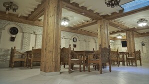 A room with wooden furniture, a brick wall, and a skylight. - BAKOVUL HERITAGE  (Bukhara)